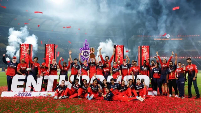 Smriti Mandhana and Sophie Devine celebrating with the WPL 2026 trophy after RCB’s final victory