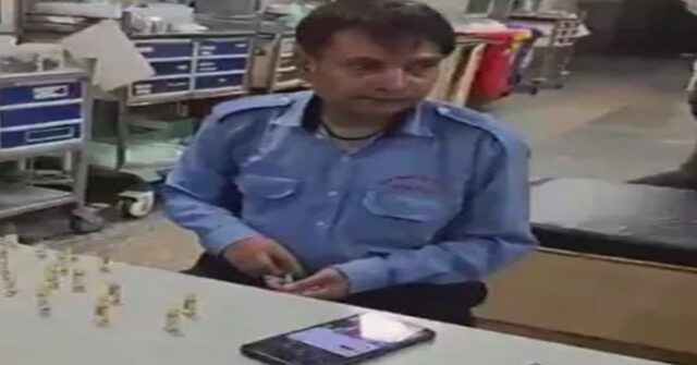 Security guard filling medicine into a syringe at Noida District Hospital